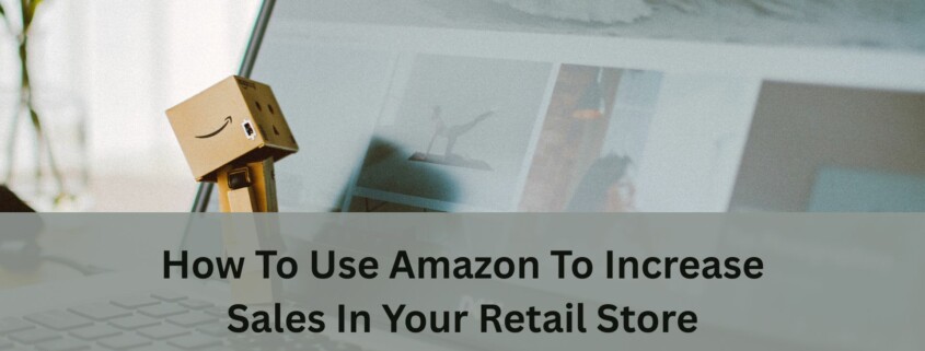 A small cardboard Amazon figure stands on a laptop keyboard in front of an open webpage, with text about using Amazon to increase retail store sales.