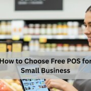 A grocery store employee in a blue uniform smiles while using a free POS system in front of produce and shelves