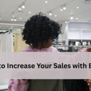 shopper in a clothing store looking at an orange and white patterned top.