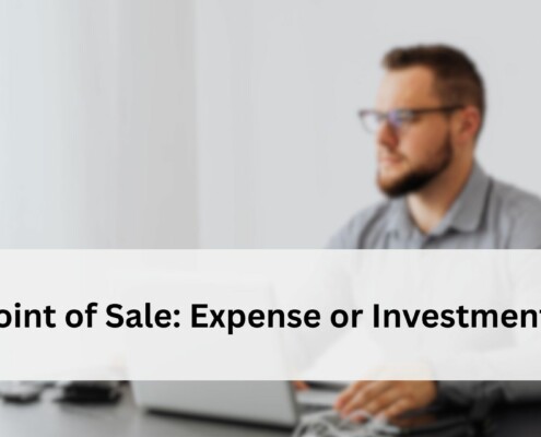 Blurred view of a man working at a desk with a laptop, representing the question of whether a POS system is an expense or an investment