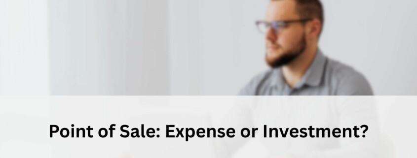 Blurred view of a man working at a desk with a laptop, representing the question of whether a POS system is an expense or an investment