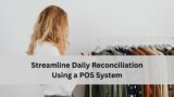 Employee reviewing clothing inventory on a rack and writing notes, representing using a POS system to streamline daily reconciliation.
