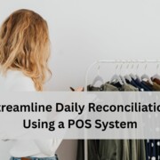 Employee reviewing clothing inventory on a rack and writing notes, representing using a POS system to streamline daily reconciliation.