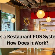 A bright modern restaurant interior with hanging globe lights, large windows, and a view of the street outside.