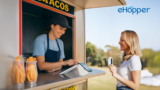 Smiling food truck employee assisting a customer with a credit card payment on a POS payment terminal