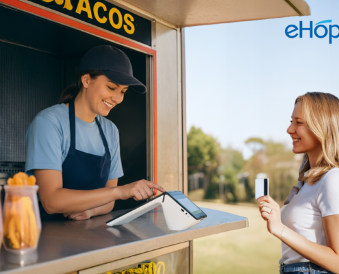 Smiling food truck employee assisting a customer with a credit card payment on a POS payment terminal